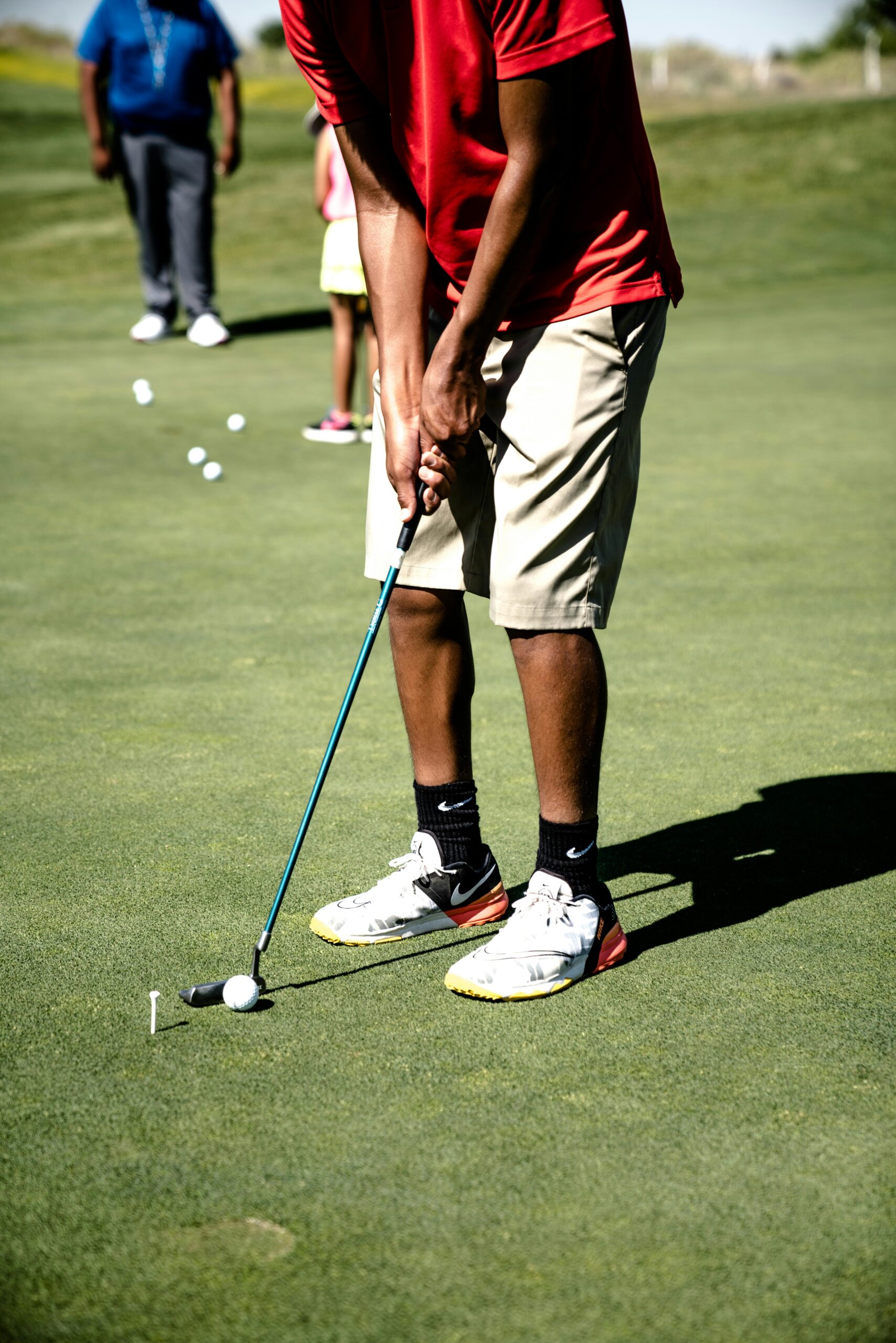 A golfer practicing a putt during a leisure game on a sunny day at the course.