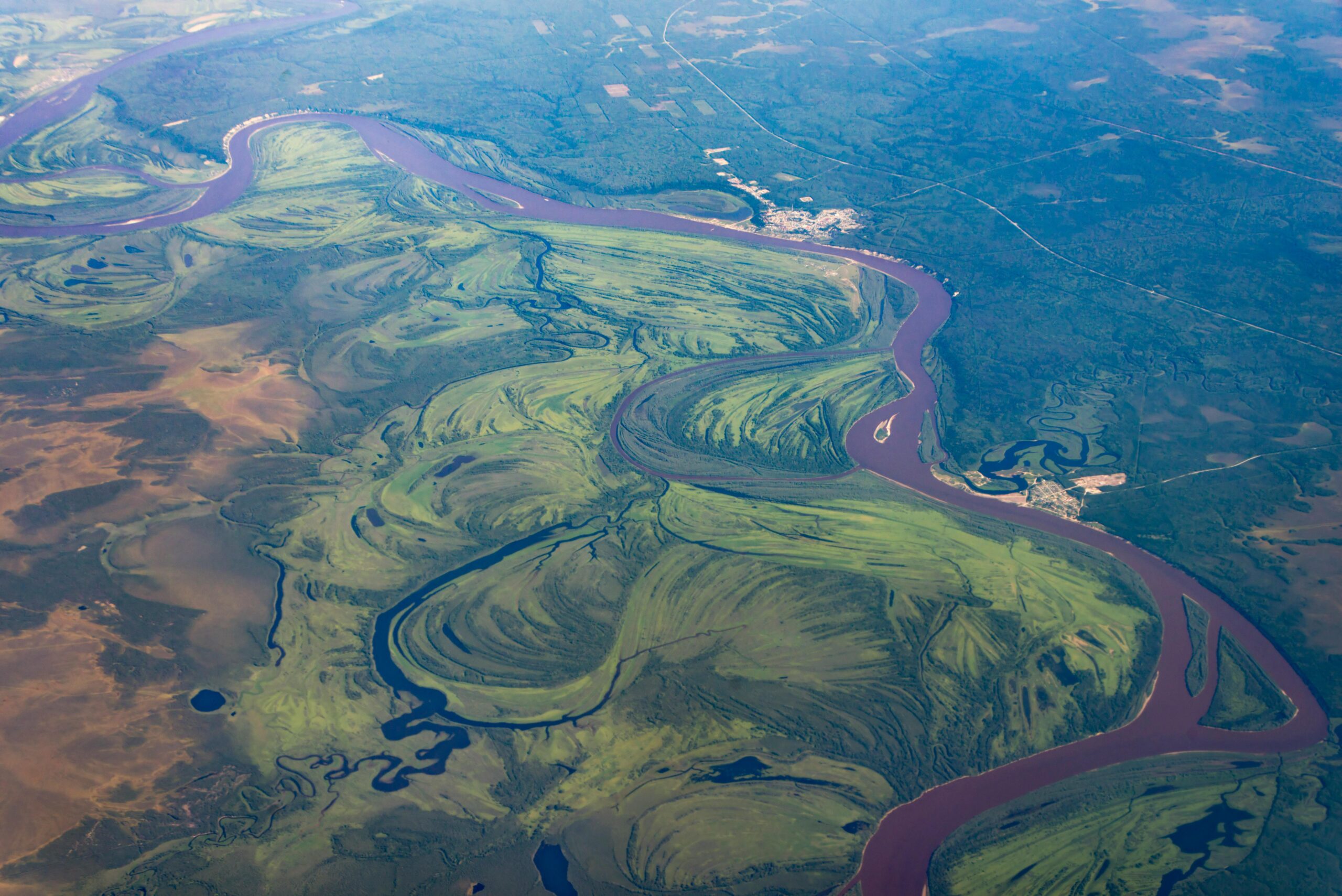 Scenic aerial landscape of river curves amidst lush greens in Khakassia, Russia.